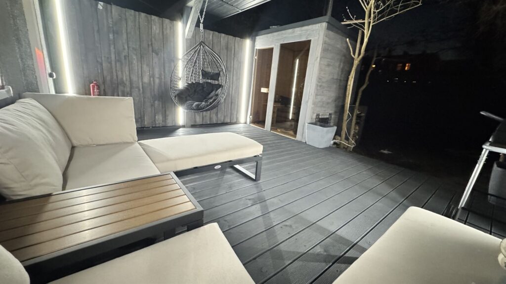 Stylowy taras w nocy z białymi meblami i wiszącym fotelem, sauna